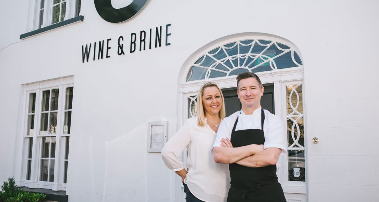 Chris and Divina standing in front of Wine and Brine