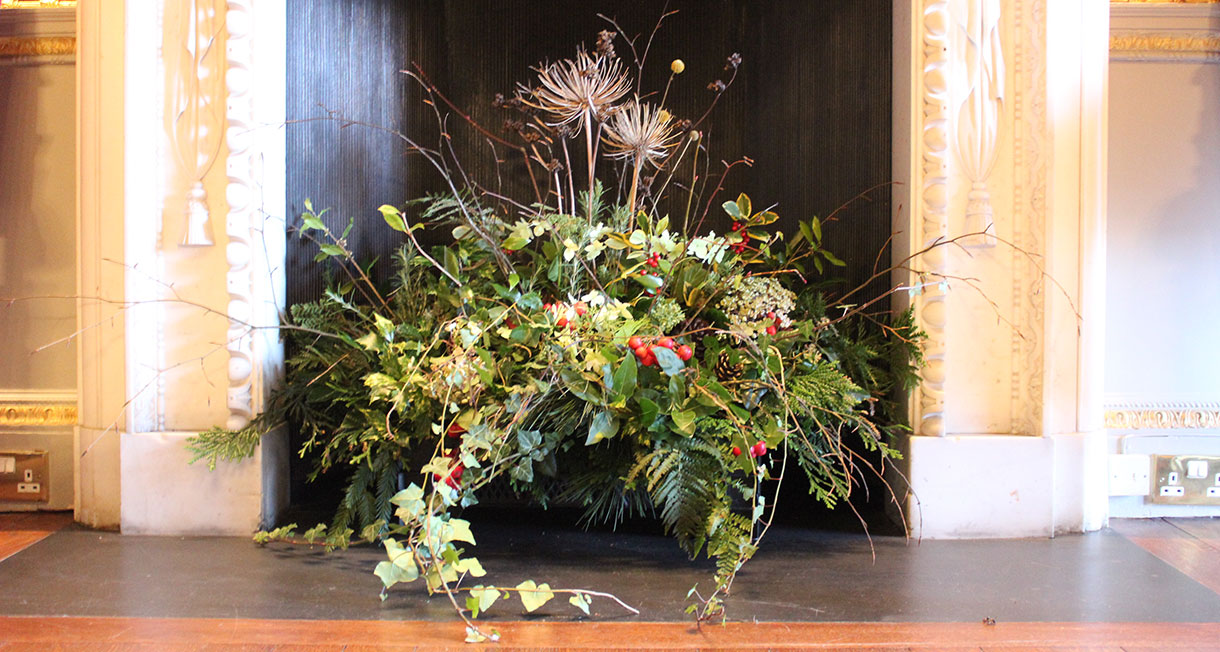 Large Christmas floral arrangement sitting on a fireplace